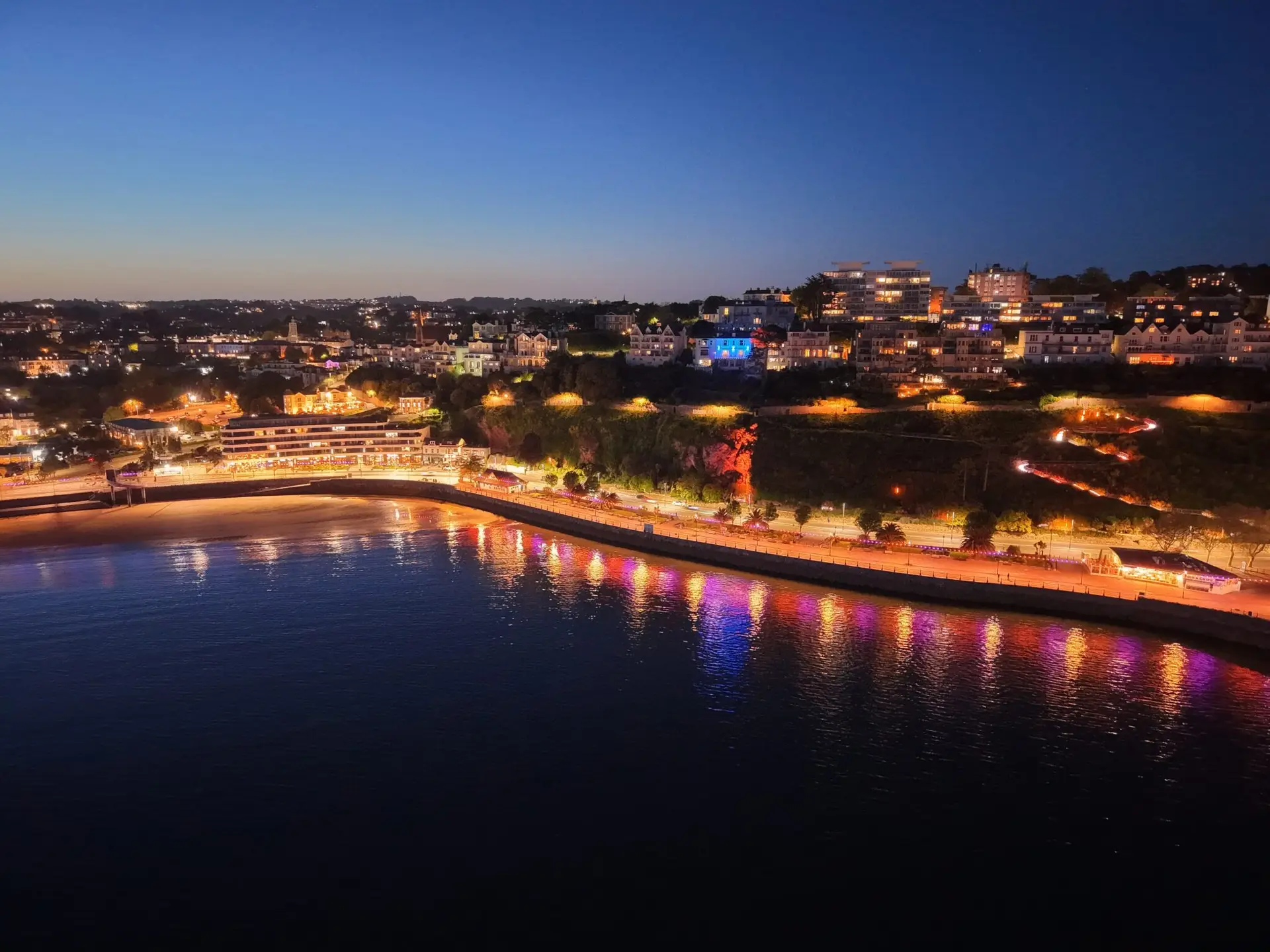 Drone image taken at night showing lights on coastline. Still taken from drone video.
